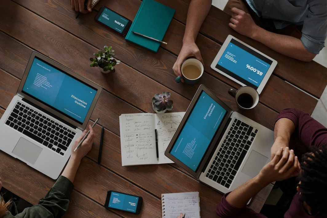 People sitting around multiple laptops